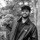 Smiling young man in leather jacket among trees, black-and-white photo
